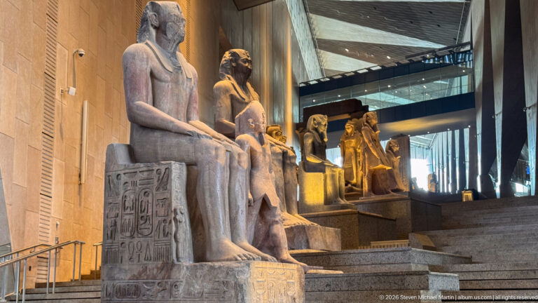 Close oblique view of seated royal statues ascending the Grand Staircase, with hieroglyphs carved on the nearest throne.