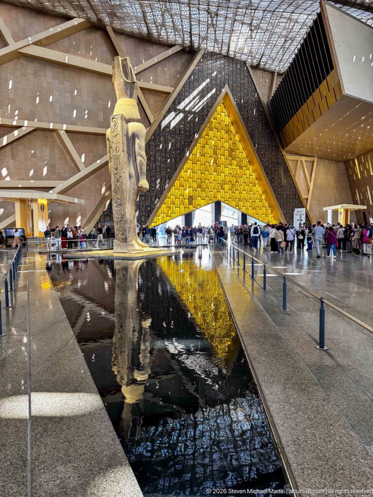 Oblique view of the colossal granite statue of Ramesses II beside a reflecting pool in the Grand Hall.