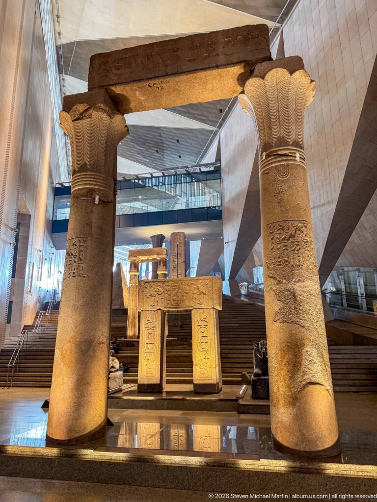 Two massive papyrus-form columns framing an inscribed ancient Egyptian stone gateway at the Grand Staircase.