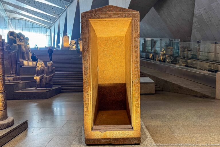 Rectangular stone shrine with a deep illuminated niche and carved border beside the Grand Staircase.
