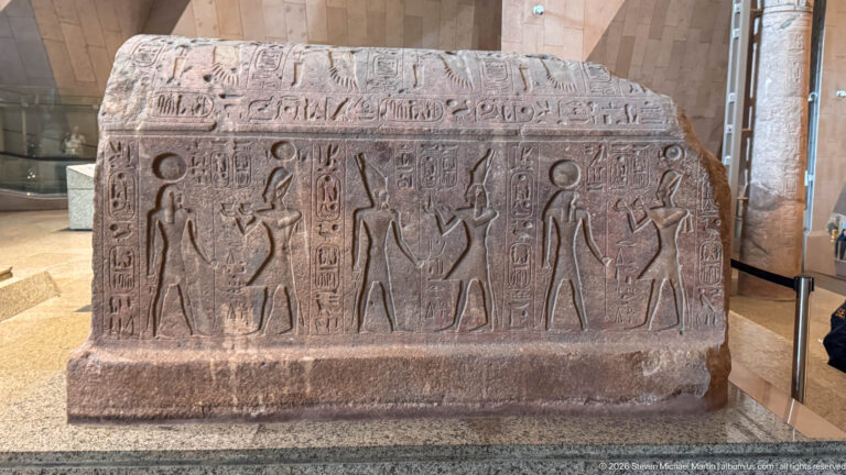 Large stone block carved with standing Egyptian figures and vertical hieroglyphic inscriptions in repeated panels.