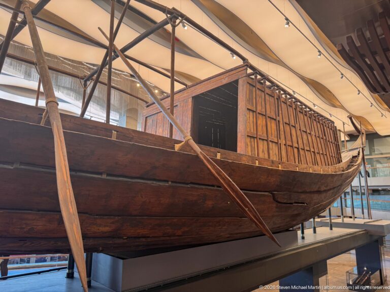 Close side view of King Khufu's First Boat with wooden hull planks, steering oars, and rectangular deck structure.