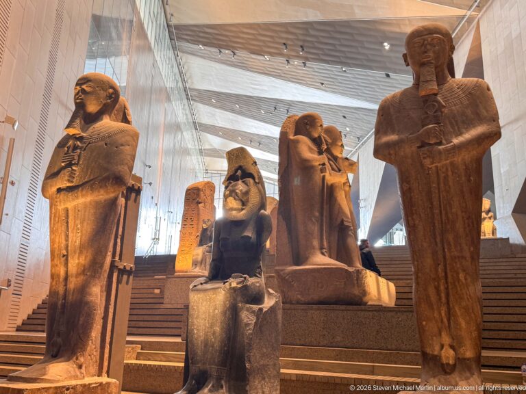 Cluster of monumental standing and seated ancient Egyptian stone statues displayed on the Grand Staircase.