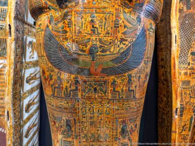 Lower anthropoid coffin painted with a winged goddess above vertical registers of deities and hieroglyphs.