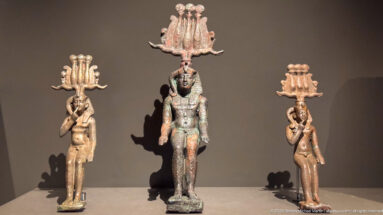 Three standing ancient Egyptian deity statuettes with tall elaborate headdresses, the central figure larger than the others.