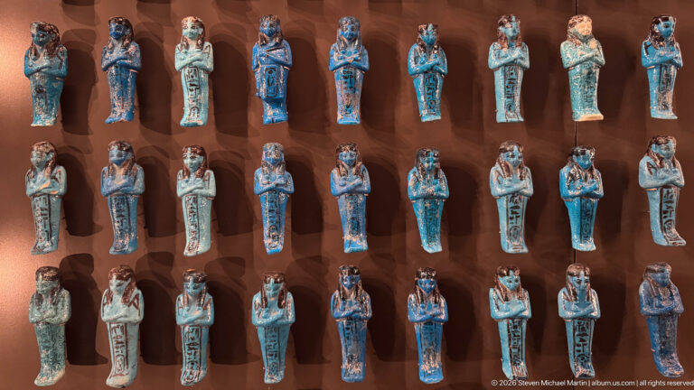 Rows of blue-green glazed ushabti figurines arranged in a museum display case.