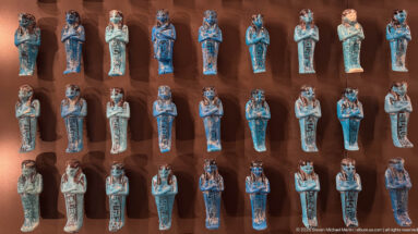 Rows of blue-green glazed ushabti figurines arranged in a museum display case.