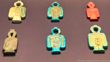 Six small looped glazed Egyptian amulets in turquoise, green, cream, and red-orange arranged in two rows.