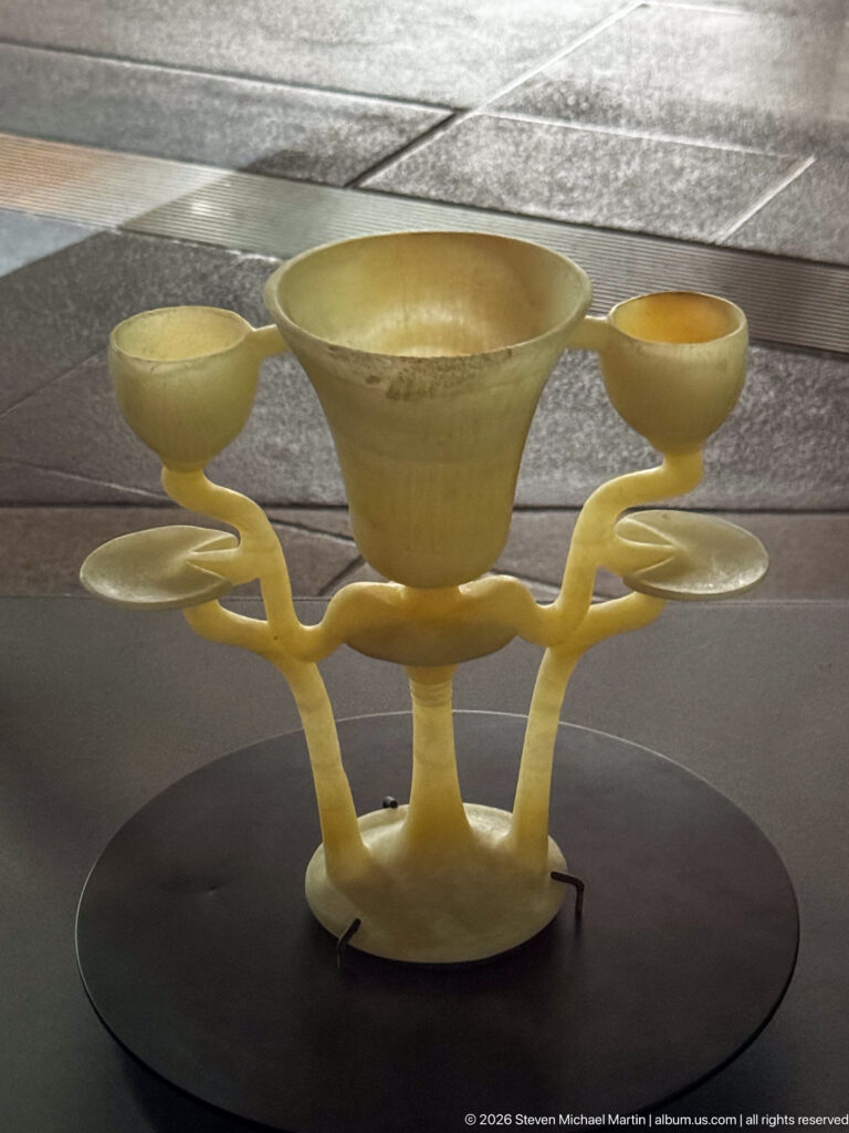 Pale translucent stone vessel with three shallow cups joined around a branching central support.