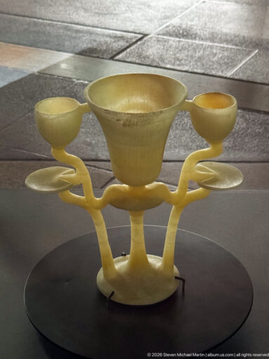 Pale translucent stone vessel with three shallow cups joined around a branching central support.