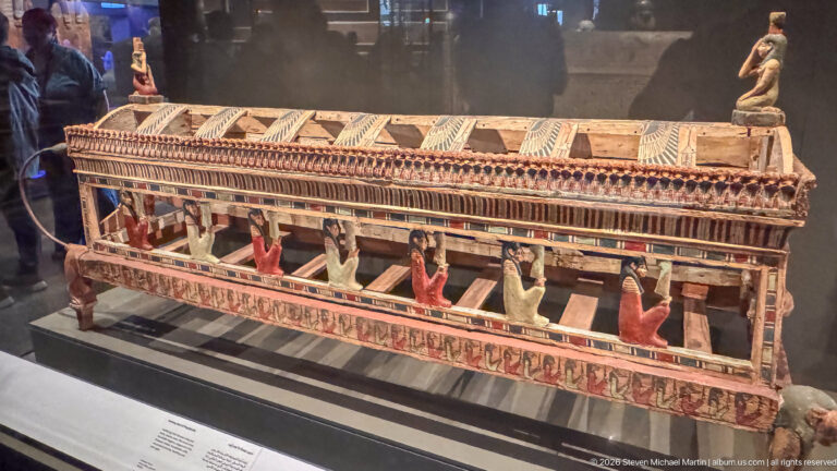 Painted wooden ancient Egyptian architectural model with a pillared structure and small standing figures.
