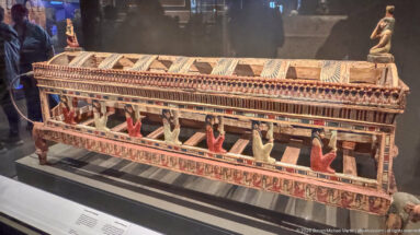 Painted wooden ancient Egyptian architectural model with a pillared structure and small standing figures.