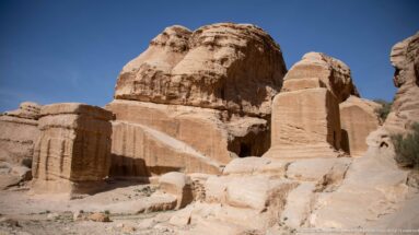 Large rounded sandstone outcrops with smooth lower faces and heavily weathered crowns beneath a clear blue sky.