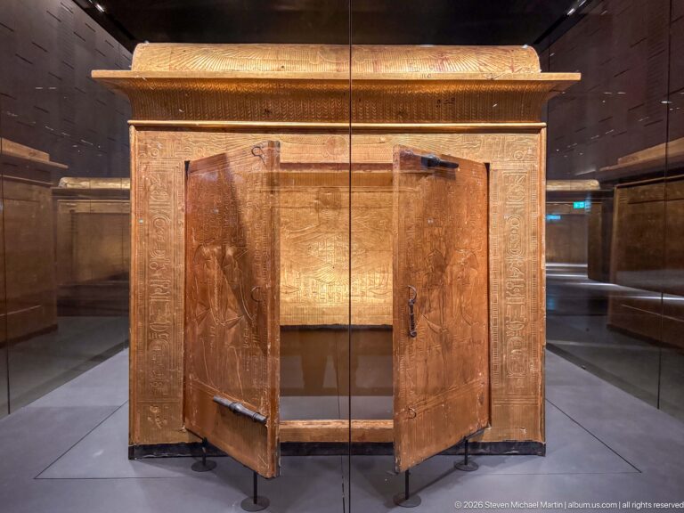 Gilded funerary shrine with both front doors open and an inscribed rear wall visible inside.