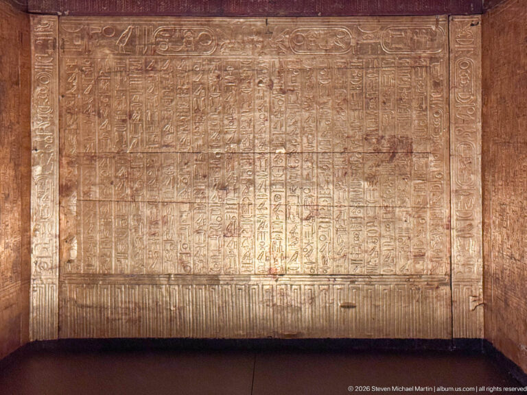 Large gilded panel filled with vertical hieroglyphic columns and small ritual figures.
