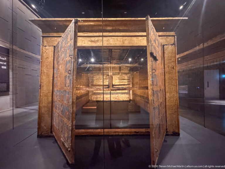 Open gilded funerary shrine with decorated double doors and a deep rectangular interior enclosure.