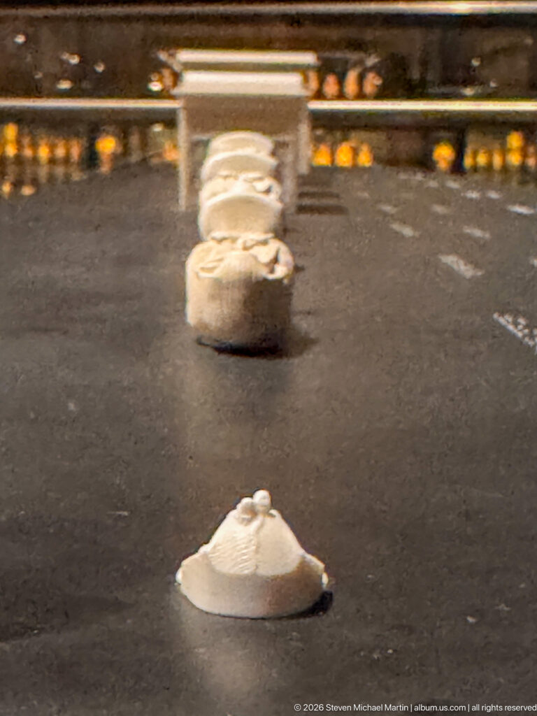Small pale carved or molded objects arranged separately on a dark museum display surface.