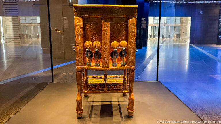 Tall gilded furniture piece with four small standing figures arranged across the front.