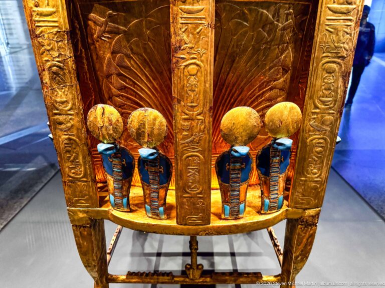 Close gilded furniture detail with four blue-and-gold captive figures arranged beneath rounded gold elements.