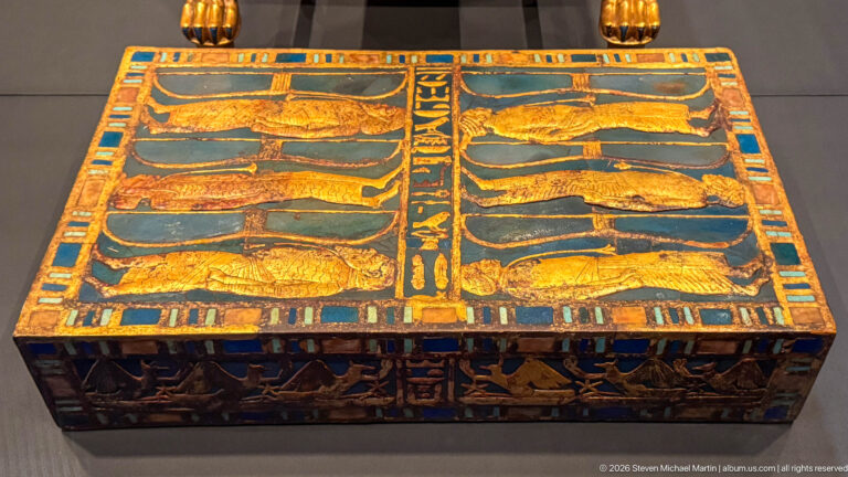 Decorated rectangular chest with paired rows of reclining animals on the lid and painted scenes on the sides.