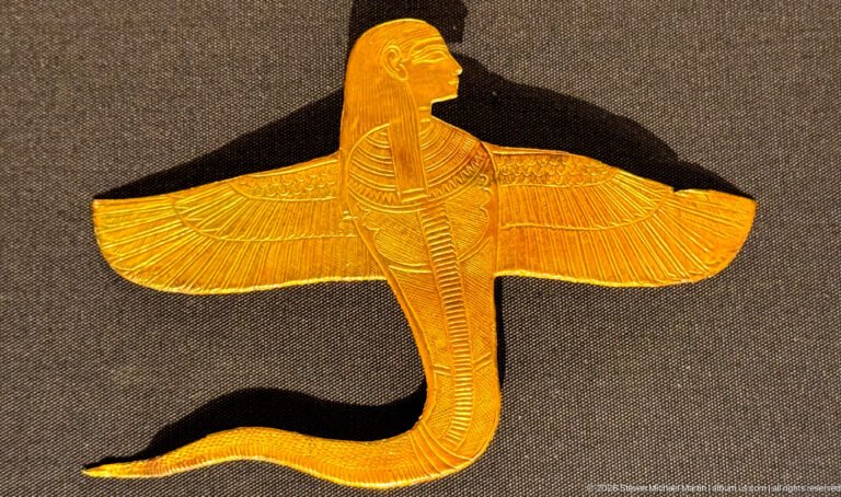 Gold winged cobra with broad feathered wings, anthropomorphic head, and long curved serpent body.