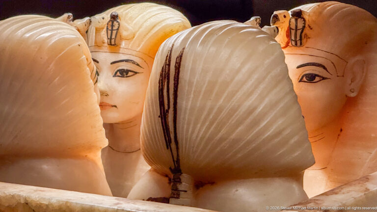 Close cluster of Tutankhamun’s four travertine canopic-chest stoppers carved as royal heads with painted eyes and wigs.