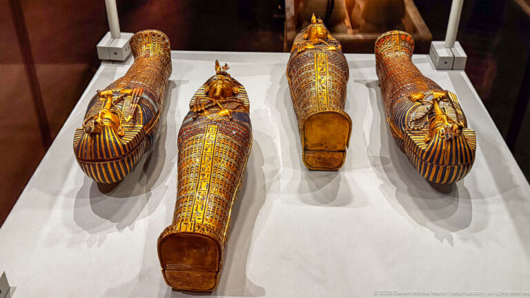 Four solid-gold canopic coffinettes of Tutankhamun with royal faces, nemes headcloths, and colored inlay.