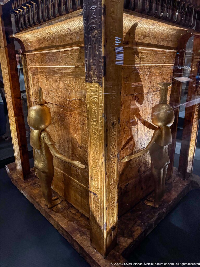 Corner of Tutankhamun’s Canopic Shrine on a Sledge with two standing protective goddesses against gilded panels.