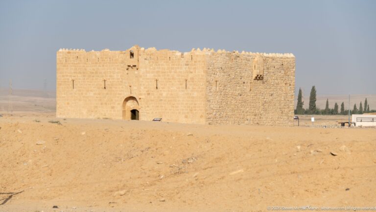 Small rectangular stone fort with arched doorway, narrow openings, and crenellated parapets in a dry landscape.