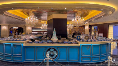 Ornate blue retail counter displaying boxed sweets and gifts beneath chandeliers and warm curved ceiling lighting.
