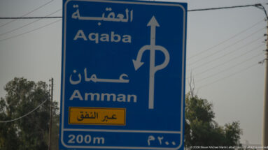Blue bilingual direction sign for Aqaba and Amman with arrows and a 200-meter junction warning.