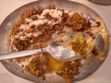 Partially eaten bean-and-yogurt mezze dish with olive oil and a serving spoon on the plate.