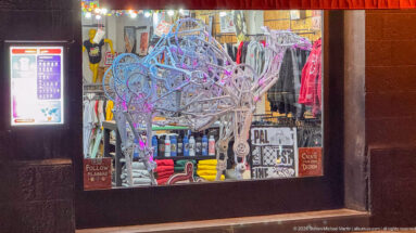 Large openwork wire animal sculpture displayed in a shop window amid colorful merchandise.