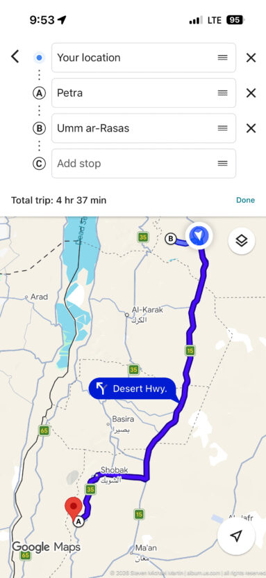 Smartphone navigation map with purple driving route toward Petra and trip time displayed above.