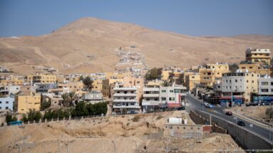 Wadi Musa buildings and roads spread across dry hills below barren sandstone-colored mountain ridges.