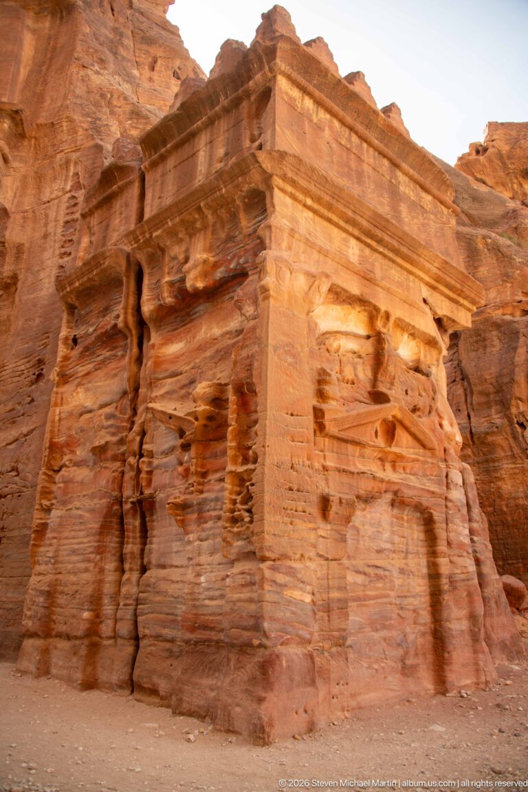 Projecting sandstone architectural corner with broad cornice and deeply weathered vertical rock surfaces at Petra.