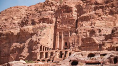 Multi-level rock-cut façade of Petra’s Palace Tomb with rows of openings, columns, and heavily eroded upper stonework.