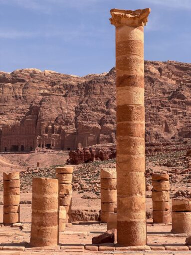 Tall re-erected column among shorter column remains in Petra’s excavated Great Temple complex.