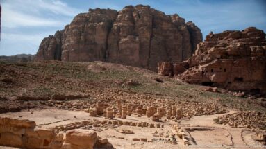 Excavated Great Temple complex with column bases, low walls, terraces, and sandstone cliffs in central Petra.