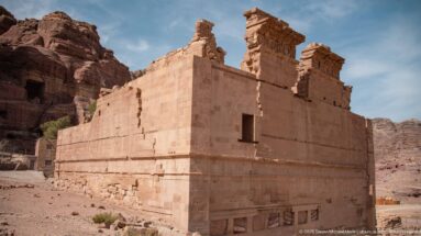 Freestanding Qasr al-Bint Temple with tall sandstone masonry walls and surviving upper architectural elements at Petra.