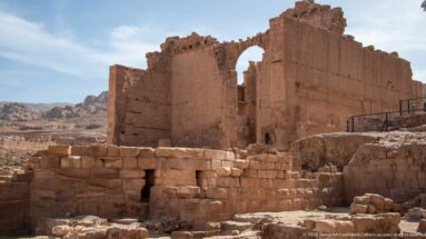 Massive freestanding sandstone walls and high opening of Qasr al-Bint Temple in Petra’s central archaeological basin.