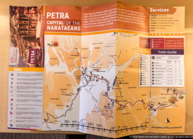Printed Petra visitor map with trails, monument symbols, service information, and visitor rules displayed at the site entrance.