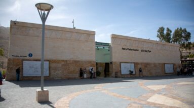 Petra Visitor Center in pale stone facing a paved plaza, with bilingual signs and ticket office area.
