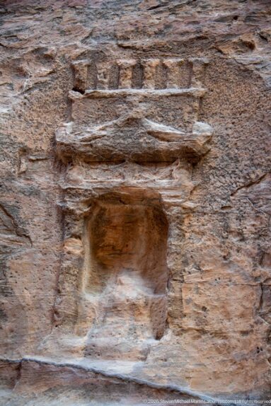 Small weathered rock-cut niche with shallow side elements and a pediment-like top carved into sandstone at Petra.