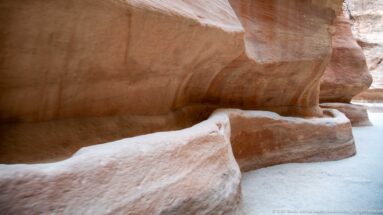 Rock-cut water channel running along the sandstone wall of Petra’s Siq beside the walking passage.