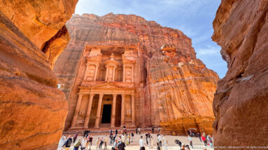 Al-Khazneh, the Treasury, appearing between the narrow sandstone walls at the end of Petra’s Siq.