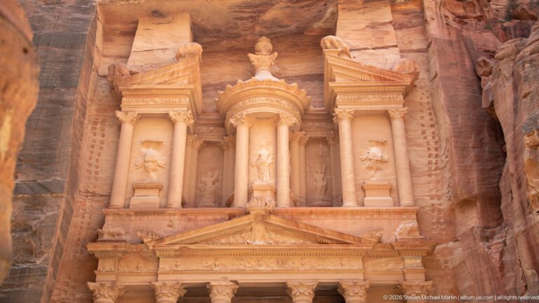 Upper story of Al-Khazneh with central tholos, flanking columns, broken pediments, niches, and crowning urn.
