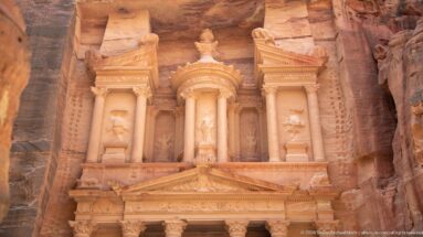 Upper story of Al-Khazneh with central tholos, flanking columns, broken pediments, niches, and crowning urn.
