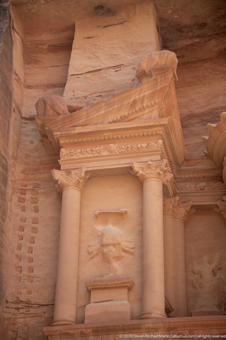 Upper Treasury niche with paired columns, triangular pediment, weathered relief, and part of the central tholos.