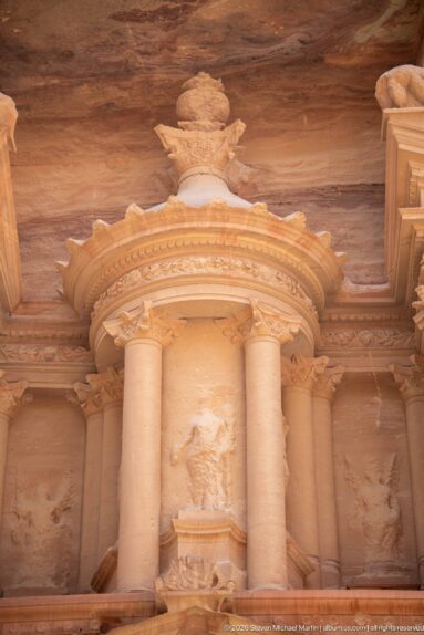 Central circular tholos of Al-Khazneh with columns, broken pediments, and large urn crowning the sandstone façade.